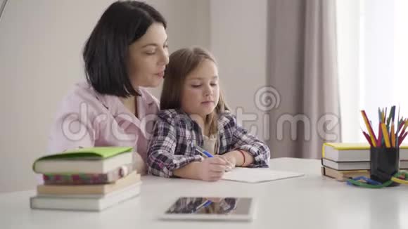 黑种人母亲帮助女儿写下的侧视图很漂亮的女学生和妈妈在家做作业视频的预览图