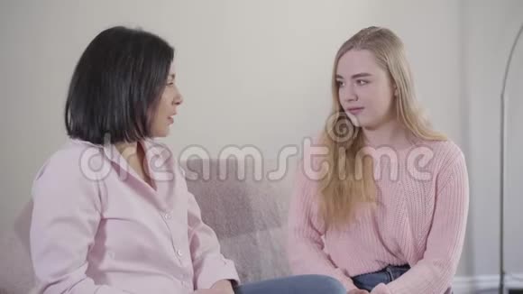 金发白种人女孩坐在沙发上和妈妈聊天的肖像十几岁的女儿和母亲在一起视频的预览图