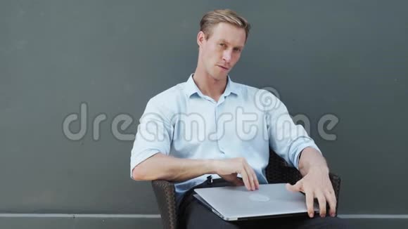 专注的年轻人坐在椅子上打开笔记本电脑开始工作灰色背景视频的预览图