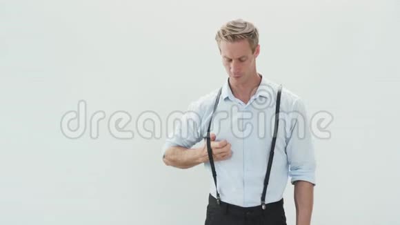 穿浅色衬衫的严肃青年脱下吊带卷起袖子视频的预览图