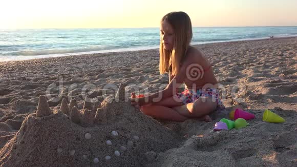 孩子在日落时在海滩上建造城堡孩子在海边玩沙子女孩在海上玩视频的预览图