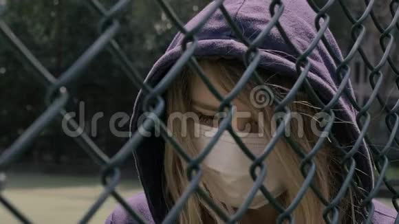 关闭边界检疫年轻女子的特写戴着护面面具站在栅栏的边界后面COVID19视频的预览图