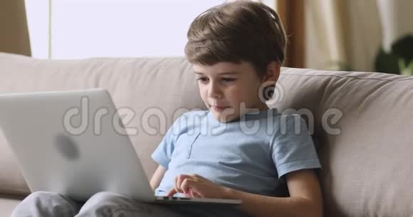 沉迷于科技快乐的小男孩在笔记本电脑上玩游戏视频的预览图