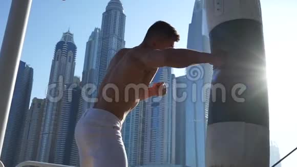 以迪拜城市景观为背景的肌肉男击打沙袋视频的预览图