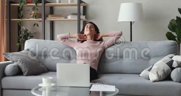 快乐的女性自由职业者从电脑工作中放松坐在沙发上视频的预览图