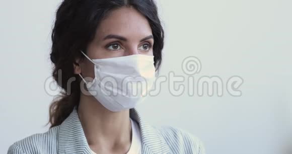 有病毒感染的年轻女子戴着面具看镜头视频的预览图