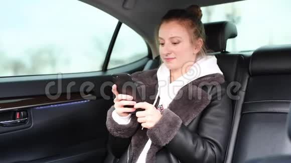 女人正在用智能手机发短信坐在出租车后座视频的预览图