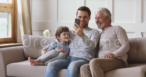快乐的三代男性家庭在智能手机上摆出自拍的姿势视频的预览图