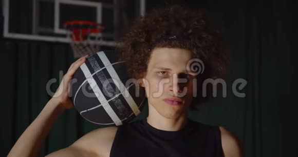流行的卷发白人篮球运动员画像严肃地看摄影记者闪光灯持球视频的预览图