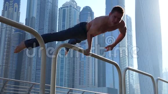 肌肉男在街上锻炼背景是迪拜的摩天大楼健康观念视频的预览图