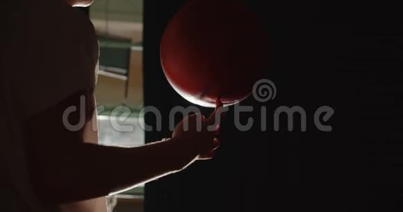 年轻的白种人篮球运动员准备在手指上旋转球明亮的光影技巧视频的预览图