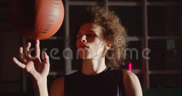 年轻的卷发白人肖像篮球运动员准备剪影旋转球在他的手指明亮视频的预览图