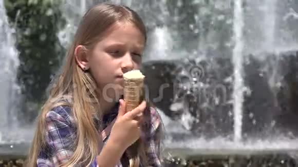 小孩在公园吃冰淇淋小孩在炎热的夏日小孩在室外喷泉旁视频的预览图