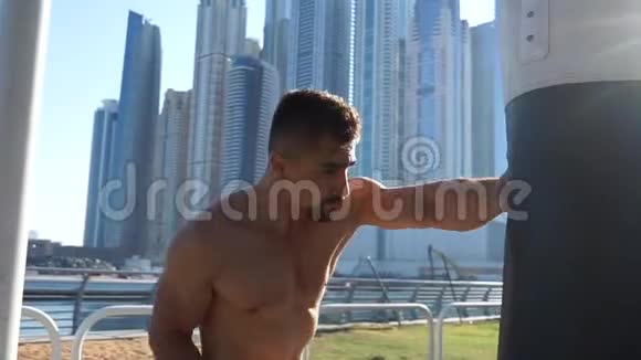 以迪拜城市景观为背景的肌肉男击打沙袋视频的预览图
