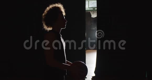 头发卷曲的白种人篮球运动员准备走上一个镶花的轮廓黑暗的后台光线视频的预览图