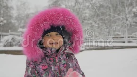 在白雪皑皑的冬天公园里可爱的可爱的宝贝女孩户外特写照片视频的预览图