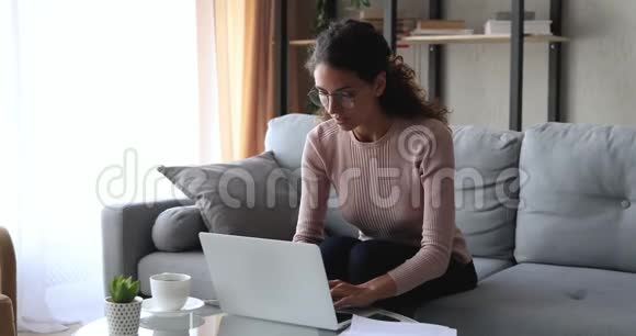 喜出望外的年轻女子用笔记本电脑在家里读着好消息视频的预览图