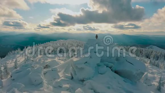 无人机飞行徒步旅行者站在雪山顶的岩石上欣赏风景视频的预览图