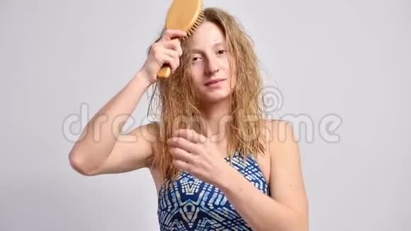 美丽的女人正在梳湿头发女孩试图梳理缠绕的头发视频的预览图
