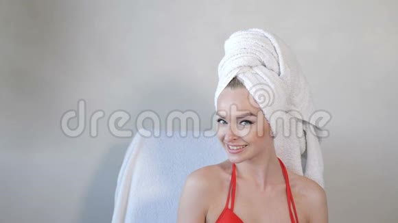 美丽的年轻微笑女人的肖像头上戴毛巾在豪华健康中心对着镜头微笑着复制视频的预览图