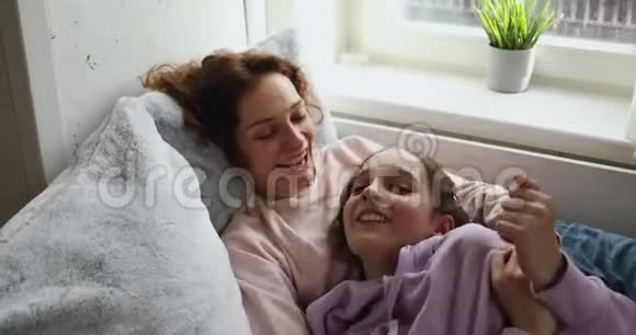 快乐的母亲和青春期的女儿在家玩着挠痒痒视频的预览图