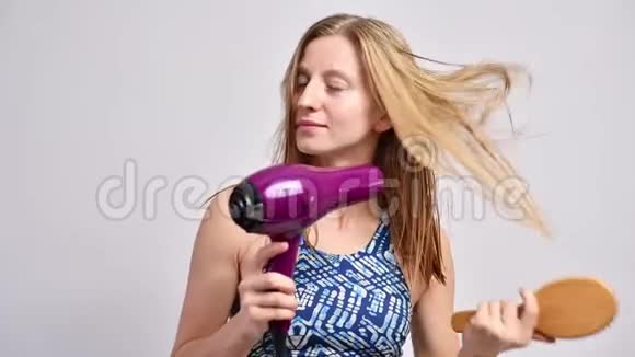 淋浴后的漂亮女人用吹风机吹干头发视频的预览图