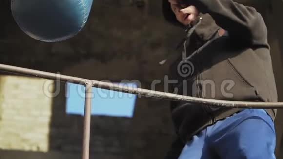 白人男孩拳击手在一座废弃建筑的背景下打拳击袋拳击和武术慢动作视频的预览图