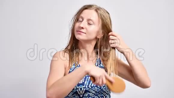 美丽的女人用木毛刷刷她湿漉漉的头发视频的预览图
