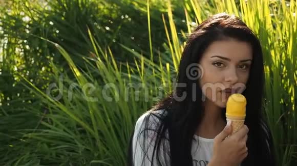 年轻美女微笑着吃着黄色高清电视里的冰淇淋视频的预览图