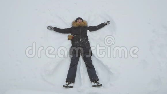 幸福的女人躺在雪地上做雪天使视频的预览图