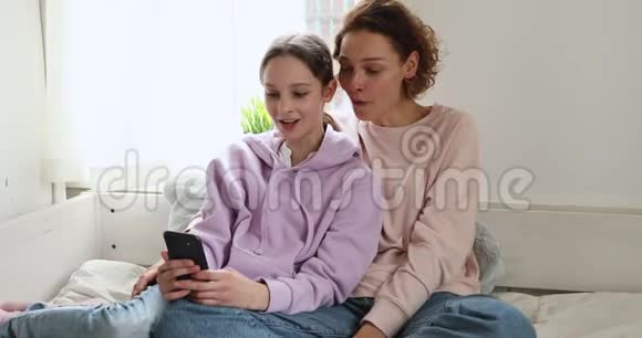 快乐的小女儿和妈妈一起玩智能手机视频的预览图