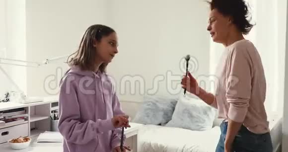 快乐的妈妈和十几岁的女儿跳舞一起在家唱歌视频的预览图