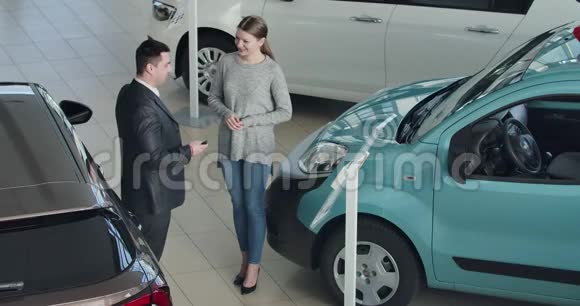 从年轻的白种人经销商给幸福的女主人车钥匙的俯视图陈列室卖汽车的商人视频的预览图