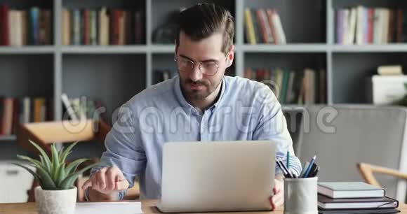 专注的商人在办公桌上的笔记本电脑上打字视频的预览图