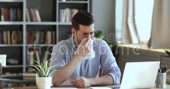 生病的男工坐在工作场所用纸巾吹鼻子视频的预览图