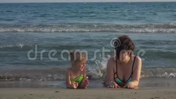 妈妈和女儿趴在海边脚悬空视频的预览图