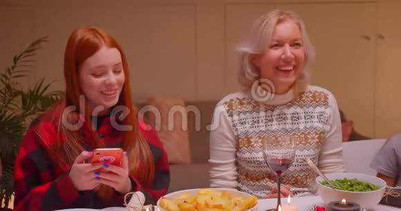不同世代的祖母和孙女使用智能手机圣诞晚餐视频的预览图