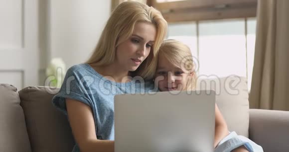快乐小妈妈抱着可爱的小孩子一起看动画片视频的预览图