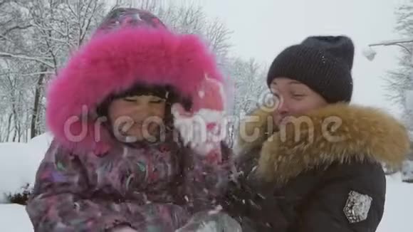 快乐的妈妈在雪地公园冬天和蹒跚学步的女儿玩耍视频的预览图