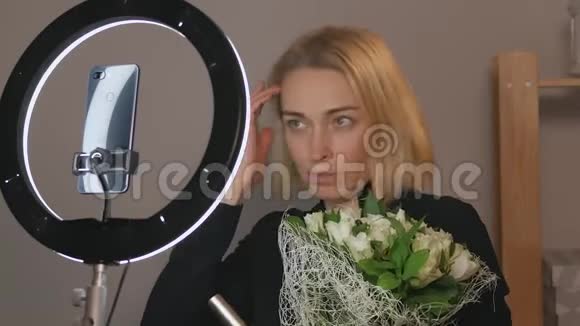 拥有一束鲜花的女性博主使用智能手机摄像头直播视频的预览图