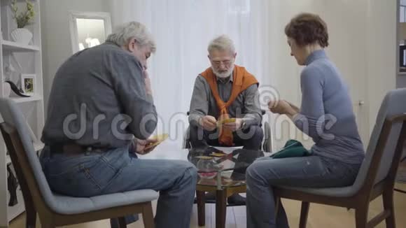自信的白人老人在桌子上打牌退休老年男女在养老院休息重点视频的预览图
