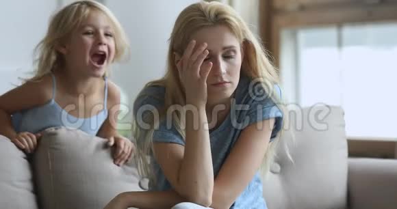精疲力竭的母亲头痛得厉害被吵闹的孩子惹恼了视频的预览图