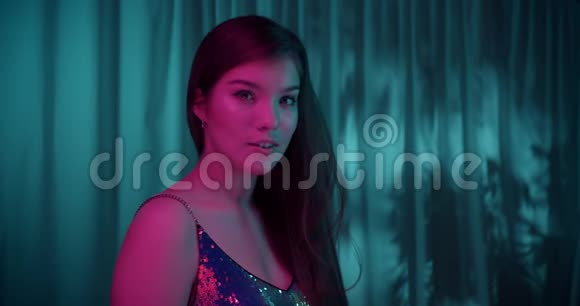 一个年轻的白种人女孩的肖像蓝色背景窗帘霓虹灯闪耀领口性感诱惑视频的预览图