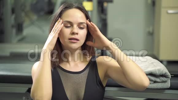 年轻有魅力的女人在健身房积极锻炼后用毛巾休息并擦拭脸上的汗水视频的预览图