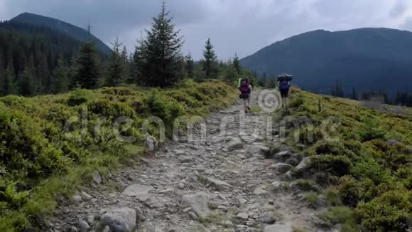 两个徒步旅行者背着背包在山上的小路上视频的预览图