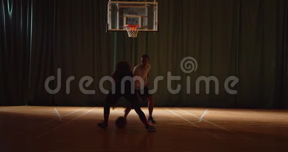两名年轻的篮球运动员打篮球比赛防守进攻夜间比赛黑暗的轮廓视频的预览图