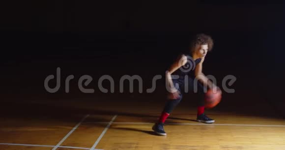 好奇的白种人篮球运动员运球镜头职业黑暗光线视频的预览图