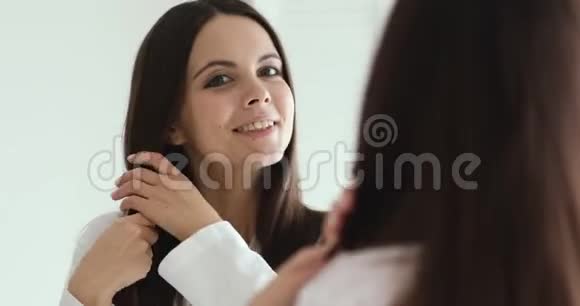 快乐自信的女孩照镜子享受健康的头发视频的预览图