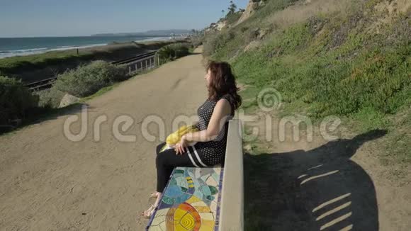 女人快乐美丽阳光明媚的夏日坐在海洋海岸五颜六色的长凳上旅行假期退休视频的预览图