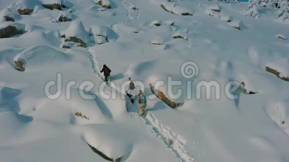 空中一群游客在晴朗的冬日爬上雪山视频的预览图